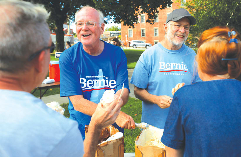 COMPANY FOUNDERS Ben Cohen and Jerry Greenfield serve their Ben and Jerry’s ice cream before a campaign rally in Dover, New Hampshire.  (photo credit: BRIAN SNYDER/REUTERS)