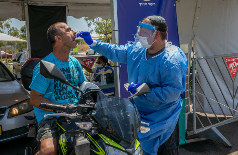 Health care workers take test samples of Israelis in a drive through complex to check if they have been infected with the Coronavirus, in Modi'in, on July 21, 2021.  (photo credit: YOSSI ALONI/FLASH90)