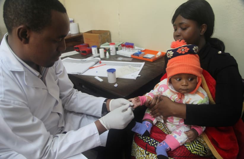 A doctor tests a child for malaria at the Ithani-Asheri Hospital in Arusha, Tanzania (photo credit: REUTERS)