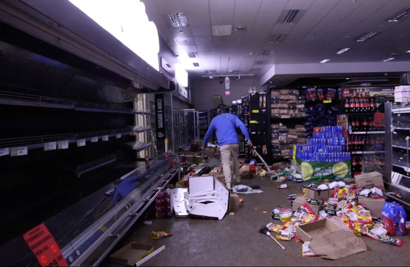 A self-armed local looks for looters inside a supermarket following protests that widened into looting, in Durban, South Africa on July 13.  (photo credit: KIERRAN ALLEN/REUTERS)