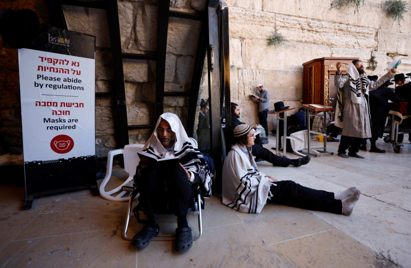 Ultra-Orthodox worshippers pray on Tisha Be’Av, the saddest day in the Jewish calendar, at the Western Wall on July 18, 2021. (photo credit: AMIR COHEN/REUTERS)