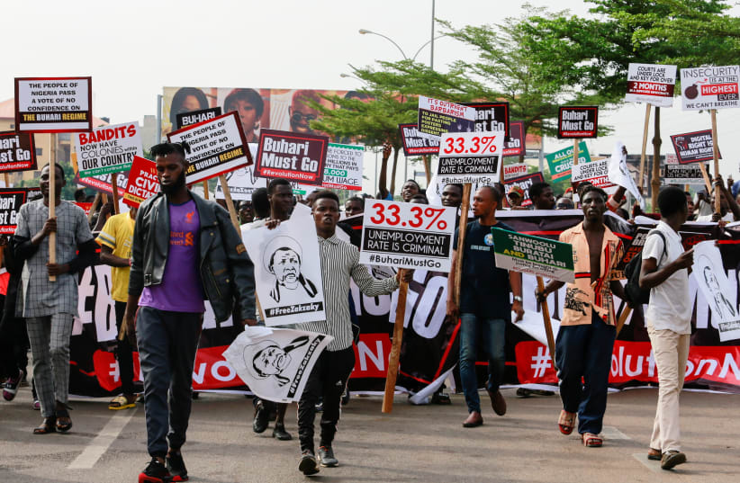 Protesters carry placards as police descend on them during a June 12 Democracy Day rally in Abuja, Nigeria June 12, 2021. (photo credit: REUTERS/AFOLABI SOTUNDE)