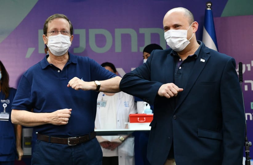 President Isaac Herzog and Prime Minister Naftali Bennett are seen kicking off Israel's third booster shot vaccinations at Sheba Medical Center, on July 30, 2021. (photo credit: HAIM ZACH/GPO)