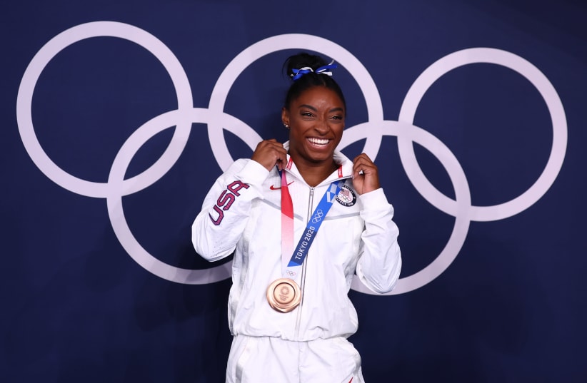 ronze medallist Simone Biles of the United States poses in front of the Olympic rings. (photo credit: REUTERS/MIKE BLAKE)