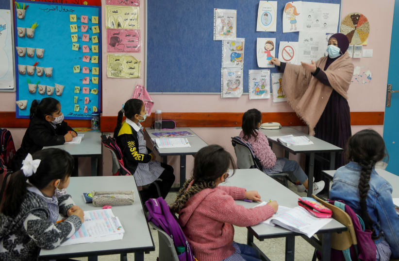 A Palestinian teacher conducts a class for students in an UNRWA-run school that reopened after the coronavirus disease (COVID-19) restrictions were eased, at al-Fari'ah refugee camp, in the West Bank April 12, 2021.  (photo credit: RANEEN SAWAFTA/ REUTERS)