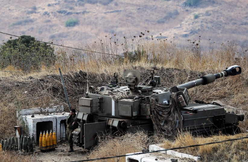 An Israeli soldier stands next to an artillery unit on the Israeli side of the Israel-Lebanon border August 6, 2021.  (photo credit: REUTERS/AMMAR AWAD)