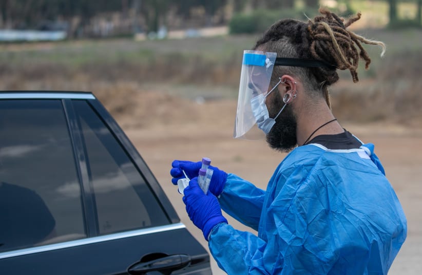  Health care workers take test samples of Israelis in a drive through complex to check if they have been infected with the Coronavirus, in Rehovot, on August 8, 2021.  (photo credit: YOSSI ALONI/FLASH90)