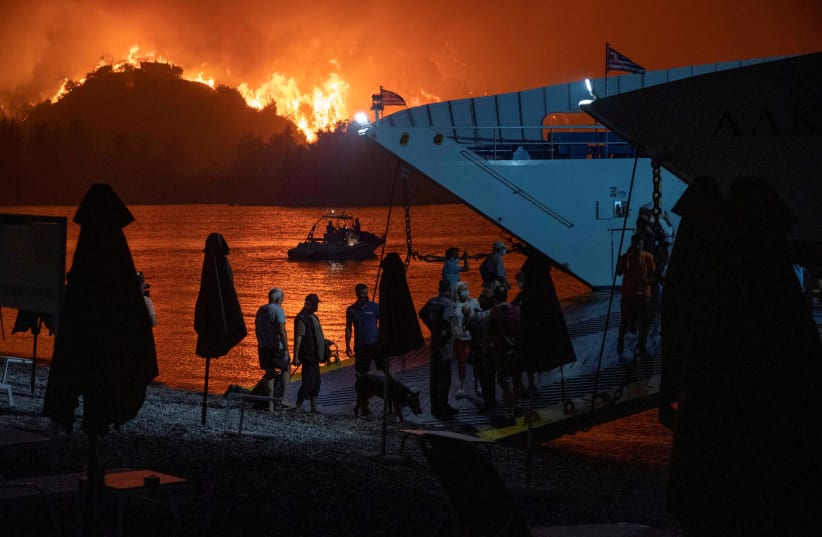 People board a ferry during evacuation as a wildfire burns in the village of Limni, on the island of Evia, Greece, August 6, 2021. (photo credit: NICOLAS ECONOMOU/REUTERS)