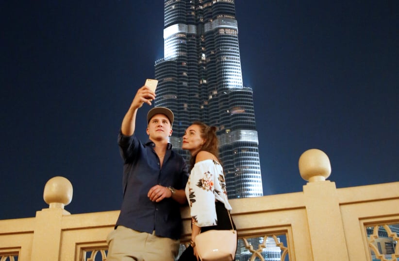  A TOURIST COUPLE takes a photo in front of Burj Khalifa, the tallest tower in the world, in Dubai, UAE. (photo credit: AMR ABDALLAH DALSH / REUTERS)