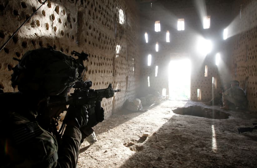  US soldier Nicholas Dickhut, from 5-20 infantry Regiment, attached to 82nd Airborne, points his rifle at a doorway after coming under fire by the Taliban while on patrol in Zharay district in Kandahar province, Afghanistan April 26, 2012.  (photo credit: BAZ RATNER/REUTERS)