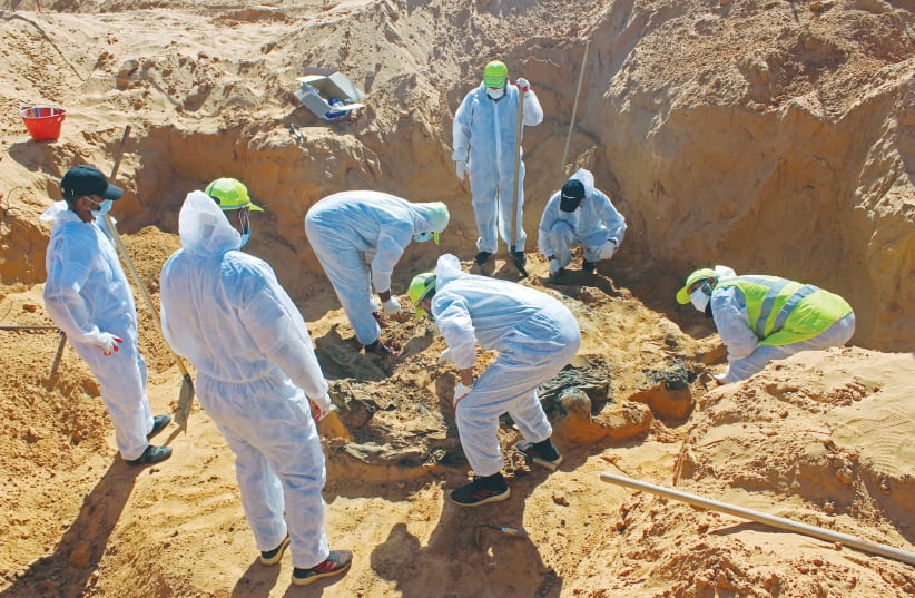 MEMBERS OF the Government of National Accord’s missing persons bureau exhume bodies in what Libya’s internationally recognized government officials say is a mass grave, in Tarhouna city, Libya, last October. (photo credit: AYMAN AL-SAHILI/REUTERS)