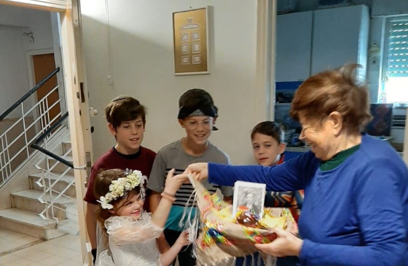  “Wrapped in Light” volunteers deliver a Purim package to an elderly woman in Jerusalem (photo credit: Courtesy)