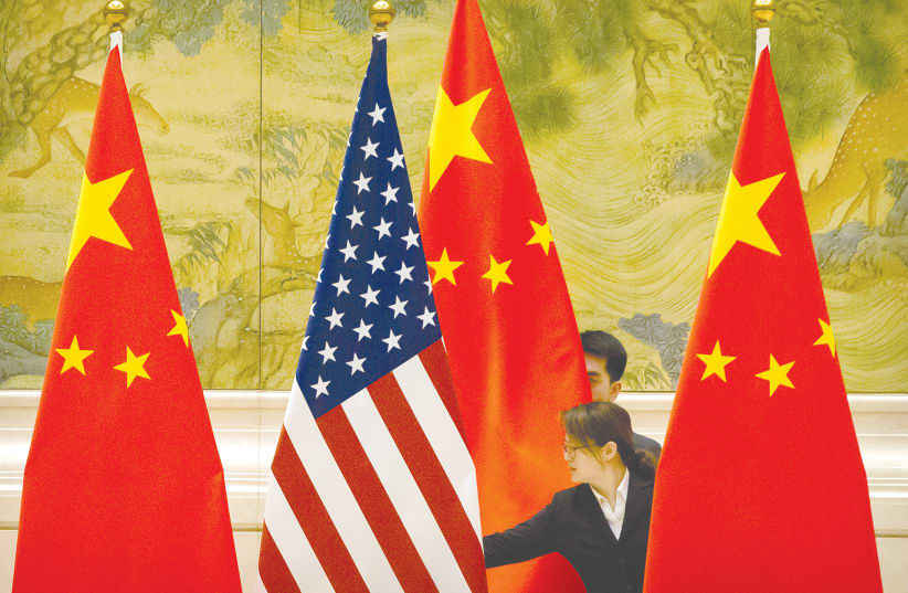 Chinese staffers adjust US and Chinese flags before the opening session of Sino-US trade negotiations in Beijing in February 2019. (photo credit: REUTERS/MARK SCHIEFELBEIN/POOL)