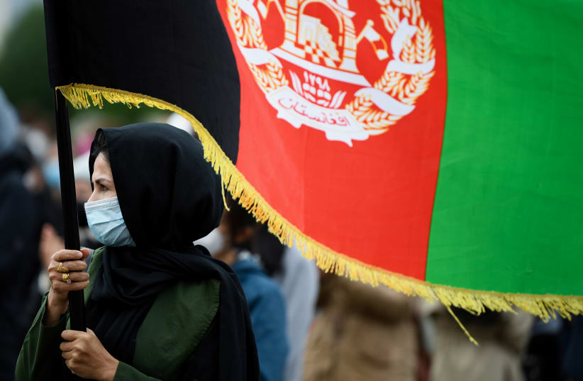  A person holds an Afghanistan's flag during a protest against support for the Taliban, in Berlin, Germany, August 17, 2021 (photo credit: ANNEGRET HILSE / REUTERS)