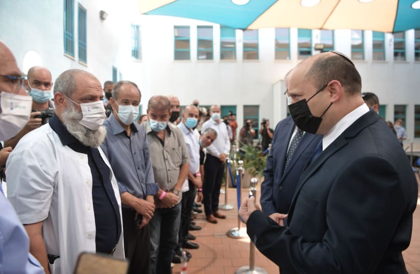  Prime Minister Naftali Bennett greets leaders from the Israeli-Arab sector during a visit to a vaccination compound in Taibe, August 19, 2021.   (photo credit: KOBI GIDON / GPO)