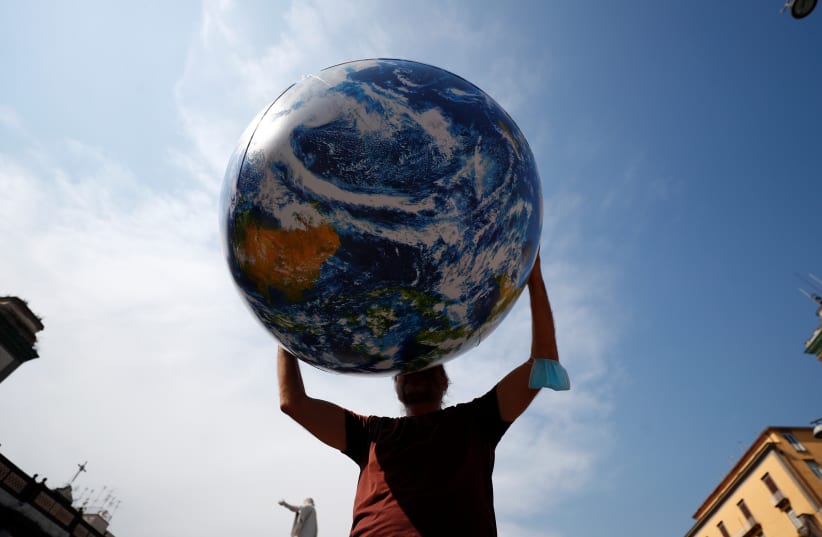  A person holds inflatable Earth as climate activists including Extinction Rebellion and Fridays for Future stage a protest demanding more action whilst G20 climate and environment ministers hold a meeting in Naples, Italy, July 22, 2021. (photo credit: GUGLIELMO MANGIAPANE / REUTERS)