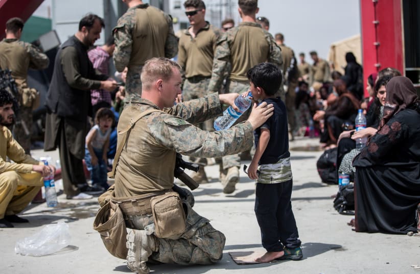  A U.S. Marine with the 24th Marine Expeditionary Unit (MEU) provides water to a child during an evacuation at Hamid Karzai International Airport, Kabul, Afghanistan, in this photo taken on August 20, 2021 (photo credit: SGT SAMUEL RUIZ/US MARINE CORPS/HANDOUT VIA REUTERS)