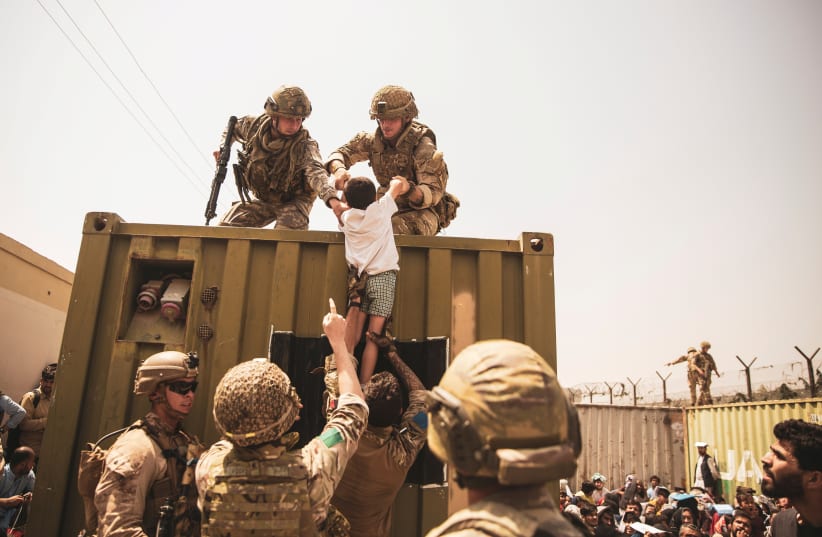  UK coalition forces, Turkish coalition forces, and US Marines assist a child during an evacuation at Hamid Karzai International Airport, Kabul (photo credit: SGT. VICTOR MANCILLA/US MARINE CORPS/HANDOUT VIA REUTERS)