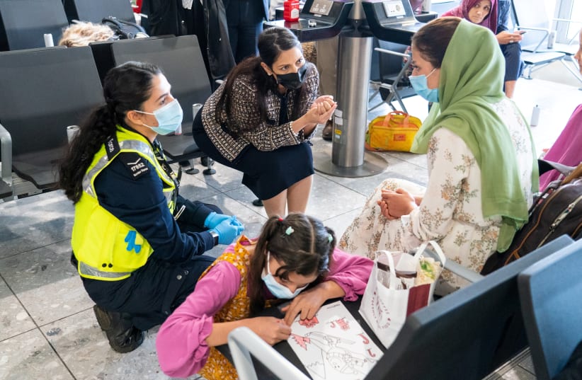  Britain's Home Secretary Priti Patel speaks to Malalai Hussiny a refugee from Afghanistan who arrived on a evacuation flight, at Heathrow Airport, in London, Britain August 26, 2021. (photo credit: DOMINIC LIPINSKI/REUTERS)