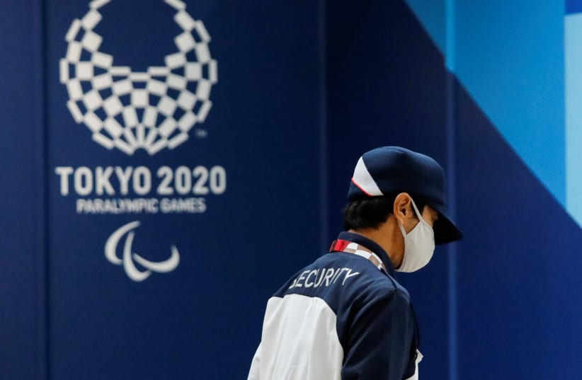  A security officer wearing a protective face mask walks past the logo of Tokyo 2020 Paralympic Games, amid the coronavirus disease (COVID-19) pandemic, in Tokyo, Japan (photo credit: REUTERS/ISSEI KATO)