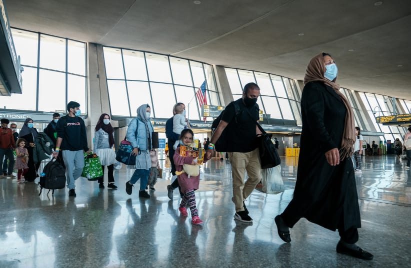  Afghan refugees walk to a bus taking them to a processing center upon arrival at Dulles International Airport in Dulles, Virginia, US. (photo credit: MICHAEL A. MCCOY/REUTERS)