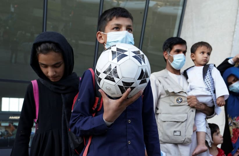  A boy holds a soccer ball as he and other Afghan refugees board a bus taking them to a processing center upon arrival at Dulles International Airport in Dulles, Virginia, US. (photo credit: KEVIN LAMARQUE/REUTERS)