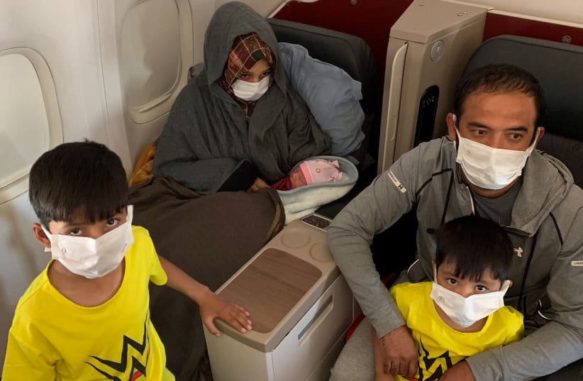  fghan evacuee Soman Noori, accompanied by her husband Taj Moh Hammat and their sons, holds her newborn baby girl named Havva on board an evacuation flight operated by Turkish Airlines from Dubai to Britain's Birmingham, August 28, 2021 (photo credit: TURKISH AIRLINES/HANDOUT VIA REUTERS)
