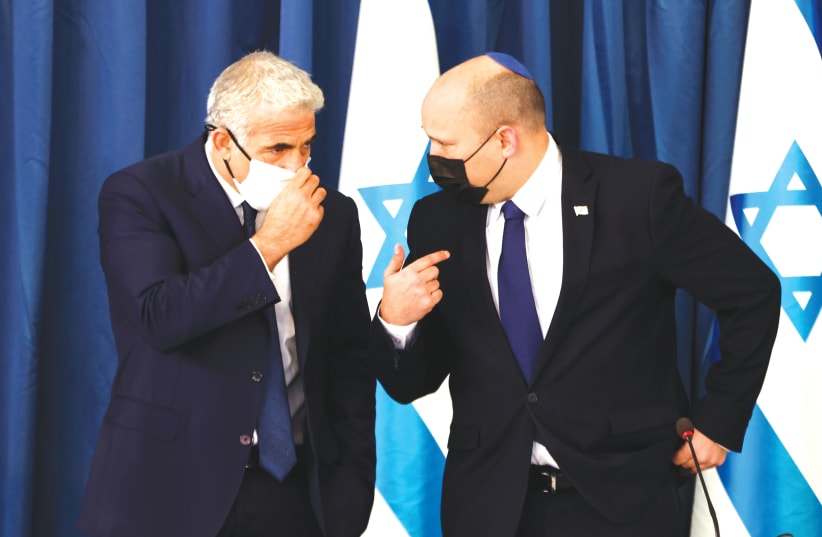  Prime Minister Naftali Bennett chats with Foreign Minister Yair Lapid at the weekly cabinet meeting, August 2021 (photo credit: RONEN ZVULUN/REUTERS)