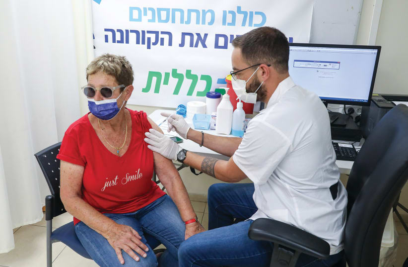  A WOMAN RECEIVES her third anti-COVID vaccination at a Clalit Health Fund center in Jerusalem.  (photo credit: MARC ISRAEL SELLEM/THE JERUSALEM POST)