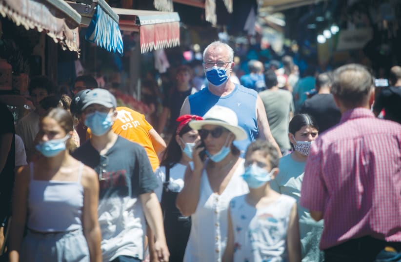  PEDESTRIANS WEAR protective face masks as they walk through the Carmel market in Tel Aviv, last month.  (photo credit: MIRIAM ALSTER/FLASH90)