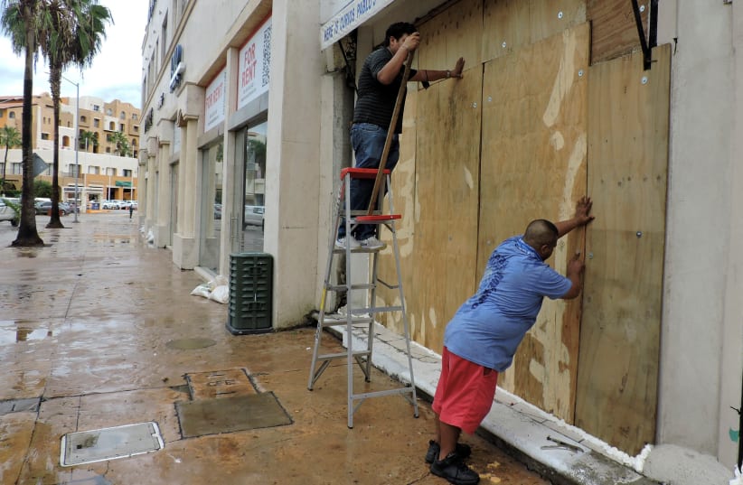  Men board up a store with plywood ahead of the arrival of Hurricane Olaf in Cabo San Lucas, in Baja California Sur state, Mexico September 9, 2021. (photo credit: REUTERS/Monserrat Zavala)