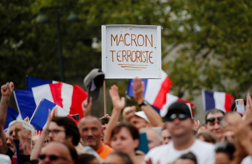  A protester holds a placard that reads "Macron terrorist" during a demonstration called by the French nationalist party "Les Patriotes" (The Patriots) against France's restrictions to fight the coronavirus disease (COVID-19) outbreak, on the "Droits de l'Homme" (human rights) esplanade at the Troca (photo credit: REUTERS)