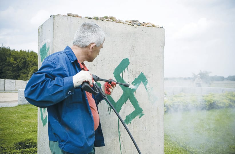  A PRESSURE hose is used to clean a monument with Nazi swastikas painted over it in Jedwabne, Poland, in this 2011 illustrative photo (photo credit: Jendrzej Wojnar/Agencja Gazeta/Reuters)