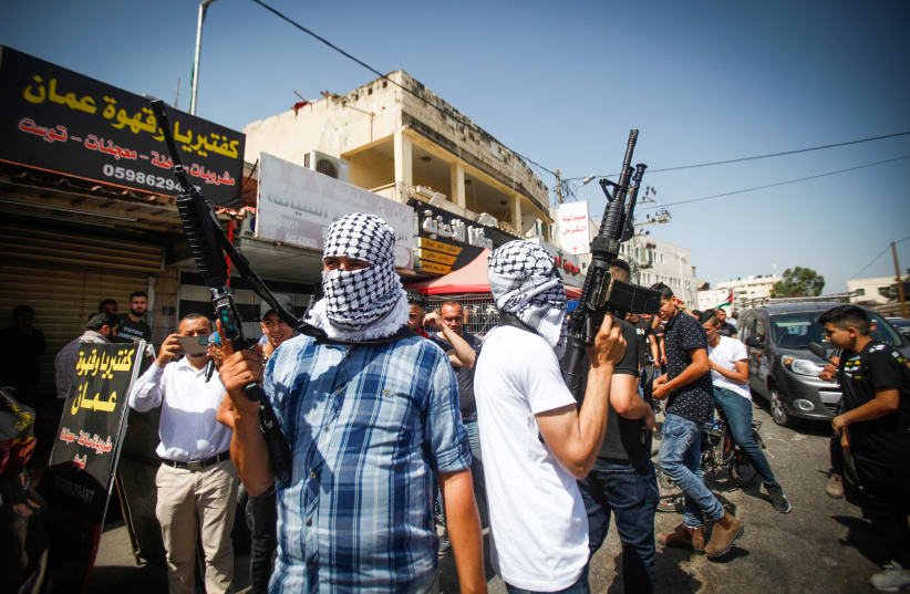  Masked Palestinians hold their guns during the funeral of Palestinian police officer Tayseer Issa, who died overnight during a shootout with Israeli security forces, in the West Bank city of Jenin (photo credit: NASSER ISHTAYEH/FLASH90)