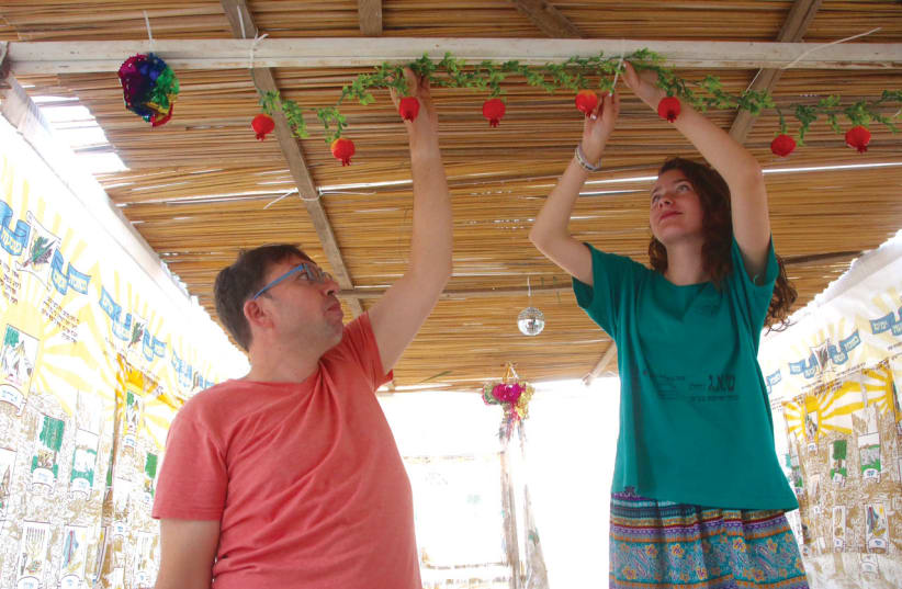  Orly and Laurent decorate their sukkah in Ma’ale Levona. (photo credit: MARC ISRAEL SELLEM)