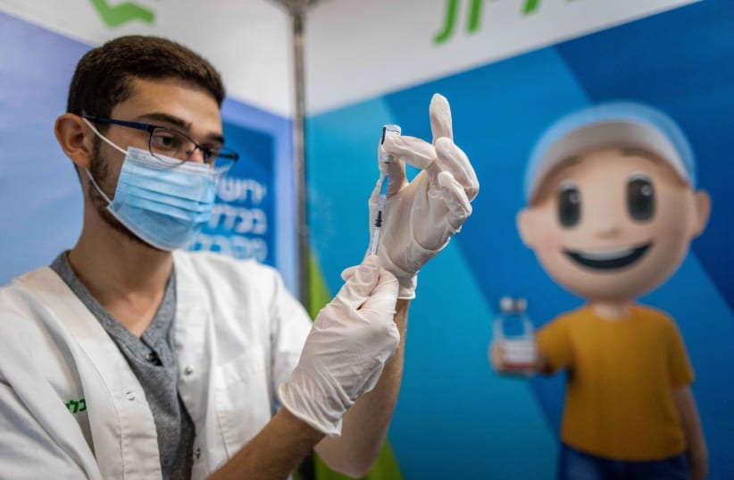  Health worker prepares a Covid-19 vaccine at a temporary Clalit health care center in Jerusalem, October 3, 2021.  (photo credit: YONATAN SINDEL/FLASH90)