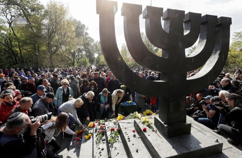  People place flowers during a ceremony at a monument commemorating the victims of Babyn Yar in Kiev (photo credit: REUTERS/GLEB GARANICH)