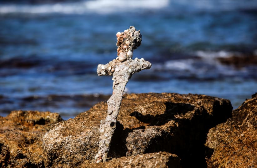  A sword believed to have belonged to a Crusader who sailed to the Holy Land almost a millennium ago stands in the water near to where it was recovered from the Mediterranean seabed by an amateur diver, the Israel Antiquities Authority said, Caesarea, Israel October 18, 2021 (photo credit: RONEN ZVULUN/REUTERS)