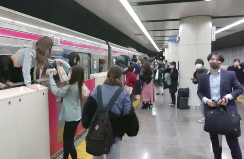People escape through windows of a Tokyo train line following a knife and arson attack in Tokyo, Japan, October 31, 2021, in this still image obtained from a social media video. (photo credit: TWITTER/@SIZ33/VIA REUTERS)