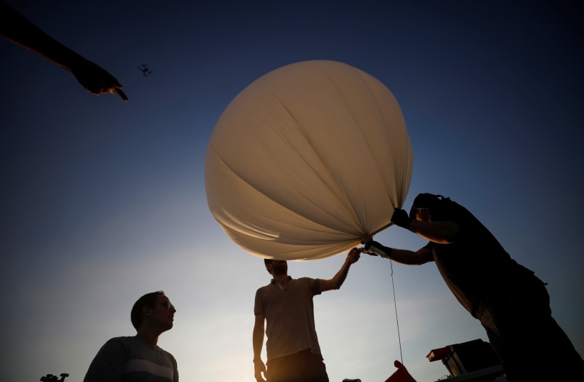 People hold a balloon during a demonstration by Israeli startup High Hopes Labs who are developing a balloon that captures carbon directly from the atmosphere at a high altitude, in Petah Tikva, Israel November 3, 2021 (photo credit: REUTERS/AMIR COHEN)