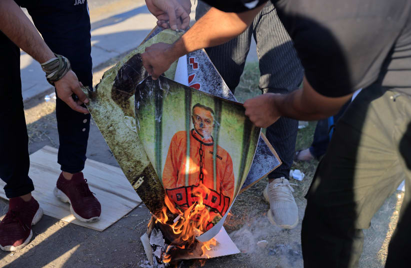  Supporters of Iraqi Shiite armed groups burn portraits of Prime Minister Mustafa al-Kadhemi and Iraq security officials during a protest against the election results near the one of the fortified Green Zone entrances in Baghdad, Iraq, November 6, 2021.  (photo credit: REUTERS/THAIER AL-SUDANI)