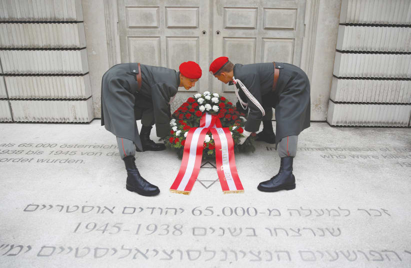  MEMBERS OF the Austrian Armed Forces adjust a wreath during a ceremony marking the 80th anniversary of Kristallnacht in front of the Holocaust Memorial in Vienna in 2018. (photo credit: Leonhard Foeger/Reuters)