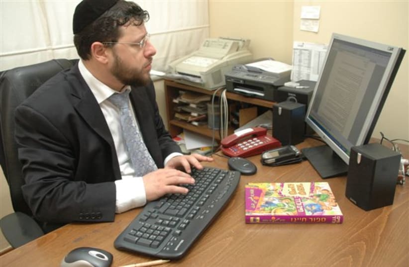  Chaim Walder in his office with a copy of his bestselling book Kids Speak (photo credit: Wikimedia Commons)
