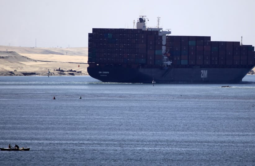  A fisherman travels on a boat with his family in front of the Zim Europa container ship, in the Suez canal near Ismailia port city.  (photo credit: REUTERS/AMR ABDALLAH DALSH)