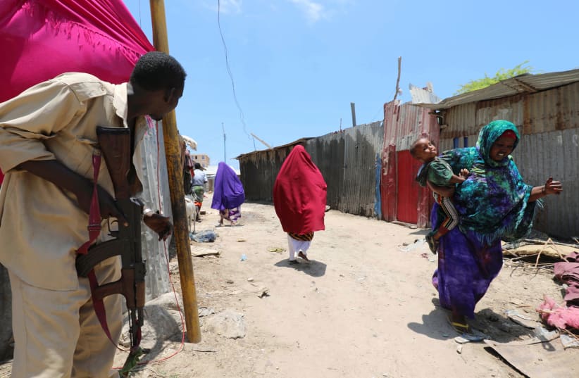 A Somali soldier holds position as civilians evacuate from the scene of a suicide explosion after al-Shabaab militia stormed a government building in Mogadishu, Somalia, March 23, 2019. (photo credit: REUTERS/FEISAL OMAR)