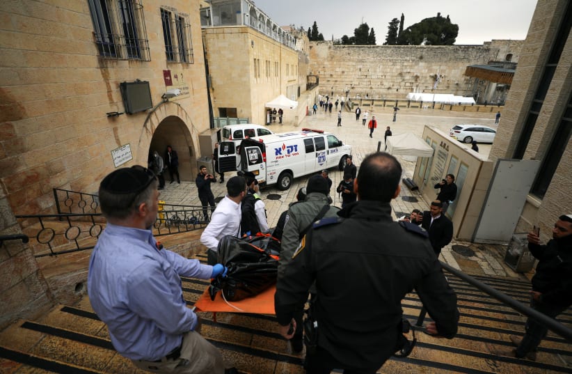  Israeli security personnel carry a dead body down the steps leading to the Western Wall following a shooting incident in Jerusalem's Old City. (photo credit: REUTERS/AMMAR AWAD)