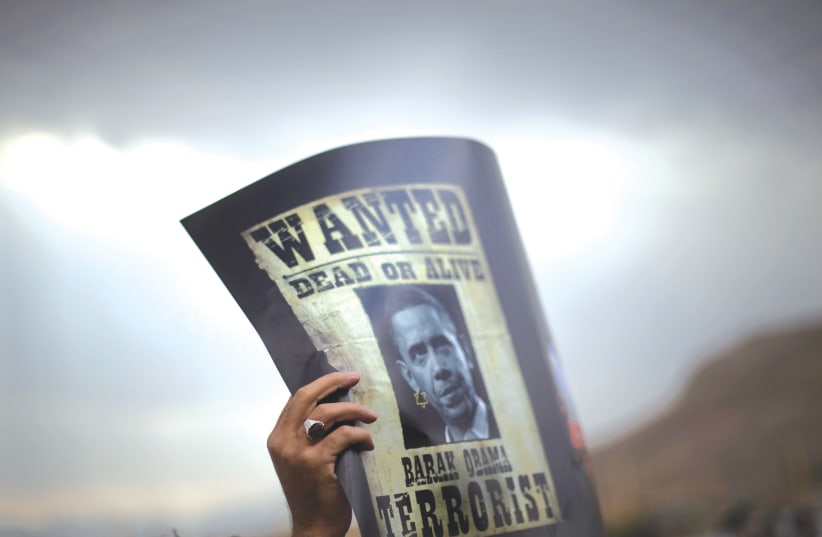  AN IRANIAN student holds a poster depicting president Barack Obama as a wanted terrorist, at a 2011 protest in support of Iran’s nuclear program, in Isfahan.  (photo credit: Morteza Nikoubazl/Reuters)