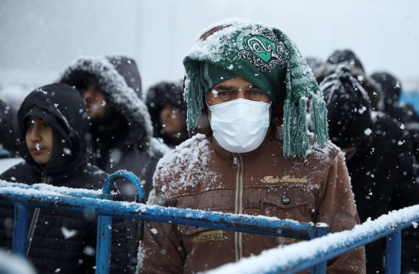  Migrants gather at a transport and logistics centre during snowfall, near the Belarusian-Polish border, in the Grodno region, Belarus. (photo credit: KACPER PEMPEL/REUTERS)