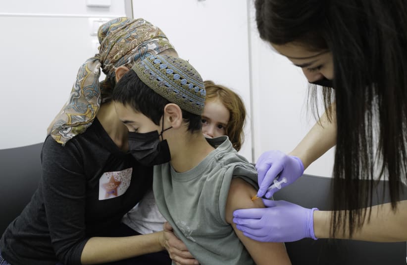  Children aged 5-11 receive their first first dose of Covid-19 vaccine, at Maccabi vaccination center in Katsrin, Golan Heights, on November 24, 2021.  (photo credit: MICHAEL GILADI/FLASH90)