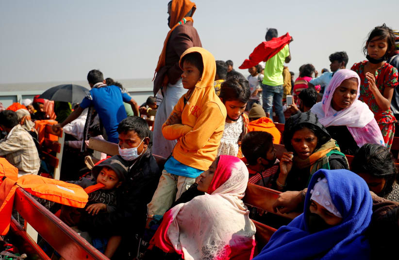 Rohingya refugees sit on wooden benches of a navy vessel on their way to the Bhasan Char island in Noakhali district, Bangladesh, December 29, 2020. (photo credit: REUTERS/MOHAMMAD PONIR HOSSAIN/FILE PHOTO)
